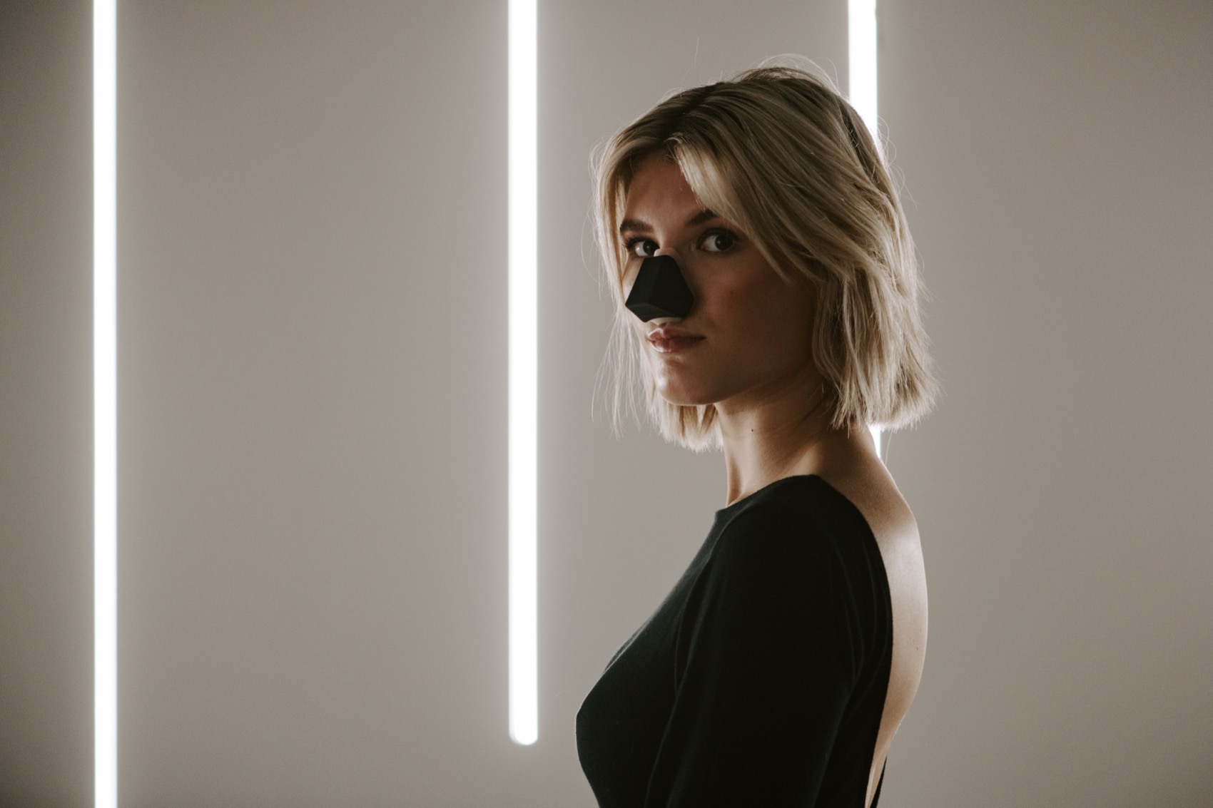 A model in profile wearing the black Nosy between two light bars