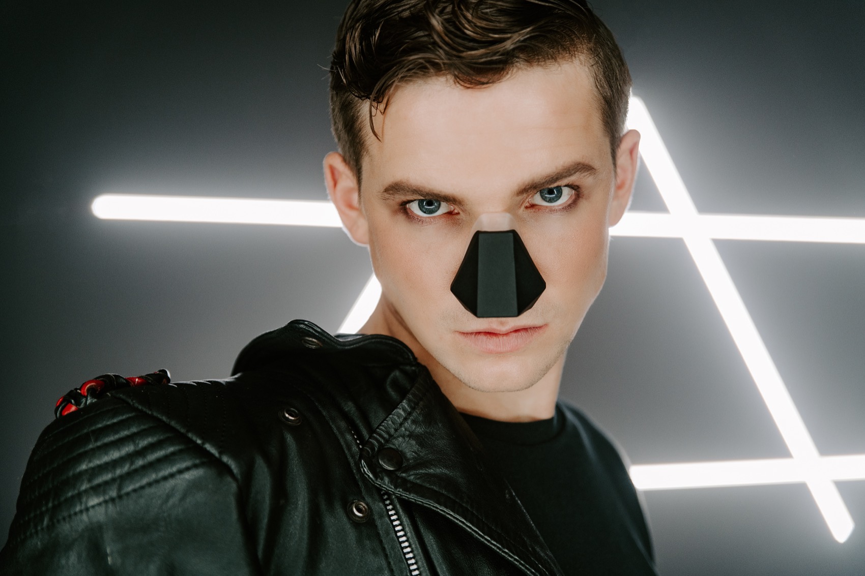 A model in a leather jacket wearing the black Nosy, staring into the camera, neon lines behind him