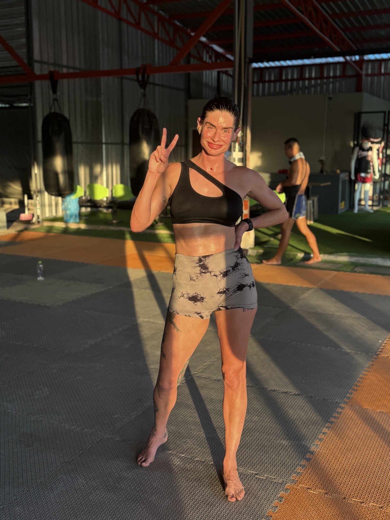 Carina at her Muay Thai gym in Phuket at sunset, making a peace sign