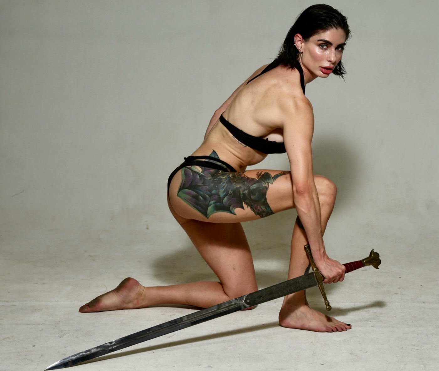 Carina kneeling as she picks up a longsword